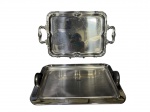 METAL INOX, duas (2) bandejas retangulares confeccionadas em aço inox, sendo: A) FORMA, lisa e com alças arqueadas em material sintético, medindo 41,5x28,5cm e B) 1 cinzelada por elementos vegetalistas em recortes na borda, medindo 53x31cm.