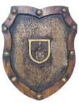 <b>DIVERSOS</b>, uma (1) placa decorativa em formato de escudo, confeccionada em resina patinada com laterais em recortes e aplicação de rebites em metal dourado, pintados em tom dourado envelhecido. Parte central com textura martelada e acabamento em pátina dourada, trazendo pequeno brasão estilizado ao centro, com elmo e campo escudo em relevo. Peça de inspiração medieval, medindo 25,5x20,5cm.