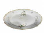 Myott, Son & Co. Ltd. (A empresa foi fundada em 1898, em Cobridge, Staffordshire), uma (1) travessa oval confeccionada em faiança inglesa na tonalidade branca, decorada por perolados e elementos vegetalistas em relevo na pasta, pintura de cestos de flores em policromia, apresenta bicados na borda, leves marcas do tempo e craquele, medindo 45x35cm.