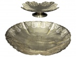 METAL PRATEADO, duas (2) fruteiras confeccionadas em metal espessurado a prata, sendo: A) 1 de pé da manufatura REGIA, cinzelado vegetalista em vazados e bordas em recortes, medindo 6x24cm e B) 1 da manufatura WOLFF, cinzelado vegetalista em vazados, falhas na prateação, mossa no fundo e pés em bola, medindo 6,5x26cm.