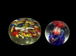 MURANOS, dois (2) pesos confeccionados em vidro de Murano, sendo: A) 1 com decoração millefiori multicolorida, medindo 5x7,5cm, possui bicados e batida e B) 1 representando peixes no fundo do mar, medindo 5,5cm.