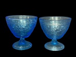 VIDROS, par (2) de taças para sobremesa confeccionadas em vidro prensado na tonalidade azul, moldado por elementos florais, cachos de uva, folhas de parreira e borda em gregas, medindo 12x12cm.