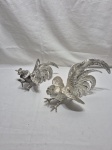 Par de galos de briga em metal prateado. Medindo o maior 21cm x 25cm de altura.