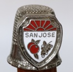 Dedal Colecionável Souvenir - San Jose, Califórnia - Metal e EsmalteBrasão frontal esmaltado com o nome da cidade e ilustrações de frutas (maçãs e uvas) sob um sol nascente