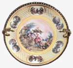 EUROPA - Magnifico centro de mesa em porcelana europeia fartamente adornada com cena galante de época em policromia e vibrante ouro, armação em bronze ormolu. Mede 31cm diâmetro.