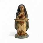 Antiga imagem sacra esculpida em madeira policromada representando Nossa Senhora da Apresentação, com manto azul e veste clara ornamentada, segurando a bandeja frontal característica. Peça de fatura popular, com policromia antiga e marcas do tempo, mantendo delicadeza, simbolismo e forte apelo devocional. Mede 16 cm.