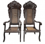 Par de poltronas e ou tronos orientais dobráveis em madeira ricamente entalhada, anglo-indiana ou birmanesa, com exuberante trabalho vazado em motivos florais, arquitetônicos e figuras simbólicas. Espaldar alto e recortado, braços curvos e assentos em palhinha natural, pés com acabamento em cabeça de de animal. Peças de grande impacto decorativo, revelando refinada marcenaria artesanal do mobiliário colonial do século XIX. Semelhantes existem no museu do oriente em Lisboa. Uma com palhinha no estado, necessita troca. Mede 1,40 cm x 66 x 90 cm.