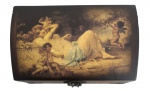 Caixa porta-joias em madeira com tampa abaulada decorada com cena clássica de querubins, ferragens em metal e interior forrado em veludo. Peça decorativa e funcional. Mede 19 x 12 cm.