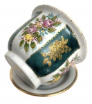 Cachepot em porcelana alemã, ricamente decorado com flores policromadas, reservas em verde e detalhes em douração, acompanhado de prato. Possui escapamento de agua. Peça refinada e decorativa. Mede 13,5 cm x 10 cm.