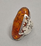 Grande anel em Prata de lei, cinzelada com estrelas vazadas e cabuchon central em Âmbar do baltico. POssui dois contrastes. Aro 16/17