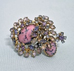 ART DECO - Antigo e grande broche europeu com estrutura em metal dourado, cravejado com pedras furtacor, liláe dois cabuchons centrais. Med 6 x 5 cm