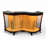 PEÇA DE ÉPOCA PARA RESTAURO  - VITRINE ANTIGA DE FORMATO SINUOSO, INFLUÊNCIA FRANCESA  FINAL DO SÉC. XIX / INÍCIO DO SÉC. XX. Elegante vitrine em madeira nobre, de desenho serpentinado, apresentando frente e laterais envidraçadas em raro formato curvo. Tampo moldurado com friso entalhado, saia recortada e pés cabriolet, características típicas do mobiliário francês de inspiração Luís XV. Interior originalmente forrado, atualmente apresentando revestimento posterior decorativo (desgastado). Estrutura com três montantes internos em metal dourado verticais. Vidros frontais e laterais íntegros, preservando a curvatura original. Peça com marcas do tempo; faltas pontuais em elementos da saia frontal; sinais de passagem de praga em painel posterior; ausência de suportes e/ou pontos de fixação para prateleiras internas (prateleiras em vidro ausentes). Necessita restauro geral para plena valorização estética do móvel. Peça estruturalmente sólida. Formato raro com proporções muito elegantes. Excelente base para restauração por profissional especializado. Medidas:167 cm (comprimento) 57 cm (profundidade total) 96 cm (altura). Este lote encontra-se em andar térreo, em prédio localizado na Av. Atlântica  Leme  Copacabana. Retirada por conta do arrematante, mediante freteiros ou transportadora especializada. Agendamento necessário pelo n. (21) 96886-7062.