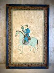 ARTE ORIENTAL - Grande (187 cm X 125 cm) painel oriental em seda pintada à mão, representando nobre falcoeiro montado a cavalo portando falcão. Peça decorativa para ambientes amplos com produção chinesa para exportação, provavelmente entre os anos de 1970 / 80. A composição inspira-se na tradição iconográfica das miniaturas persas e mogóis, com delicada paisagem vegetal ao fundo executada em desenho monocromático. Figura central ricamente colorida com trajes tradicionais e cavalo estilizado. Peça montada em amplo enquadramento decorativo com moldura laqueada azul e arabescos dourados. Apresenta rasgo na seda na lateral inferior esquerda, conforme fotografias. Medidas: 187 x 125 cm. * Atenção - Retirada e embalagem somente por transportadora. Agendamento necessário pelo n. (21) 96886-7062.