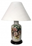 Abajur com base em porcelana pintada à mão, assinado por Maria de Lurdes. Apresenta delicado motivo floral em tons de rosa e verde, sobre fundo esfumado claro. Montado sobre base de madeira escura e cúpula de tecido. Peça de elegante presença, ideal para ambientes clássicos ou românticos. Mede 60 cm altura.