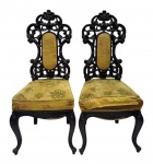 Par de cadeiras em madeira escura entalhada, espaldar vazado com rica ornamentação, pés curvos, estofamento em veludo floral tom mostarda, apresentando desgastes e marcas do tempo. No estado. Mede 1,15 cm altura.