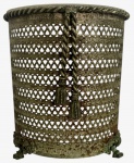 Cesto decorativo em metal vazado patinado, ricamente trabalhado, com borda superior em relevo, aplicação frontal de cordões entrelaçados com pingentes e base apoiada em quatro pés ornamentados. Apresenta oxidação compatível com a idade. Peça decorativa de grande efeito para ambientação clássica ou eclética. Mede 26cm x 23cm.