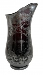 VENEZA - Elegante jarra em cristal veneziano, em tonalidade rubi com delicado trabalho em prata aplicada e rica decoração floral e arabescos gravados. Corpo bojudo com bico vertedor ondulado, interior em vermelho intenso característico da técnica sobreposta. Apresenta pátina e leves desgastes compatíveis com a idade. Peça de forte apelo decorativo e colecionável, representativa da tradição vidreira veneziana. Mede 24 cm.