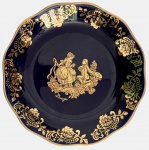 Prato decorativo em porcelana francesa Limoges, fundo azul-cobalto com rica decoração dourada, borda ondulada e cena galante clássica ao centro. Peça produzida e decorada em Limoges, França, pela tradicional Florence Limoges, com selo original no verso (Peint à la main  Made in France). Exemplo refinado da porcelana artística francesa, ideal para coleção ou decoração. Mede 10,5cm de diâmetro.