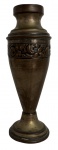Floreira de oratório em metal patinado, possivelmente bronze ou latão, com elegante corpo afunilado e base circular. Apresenta faixa central em relevo com motivos florais, acabamento escurecido e marca gravada na base, indicativa de produção antiga/industrial. Peça de caráter ornamental, adequada à decoração clássica ou coleção de objetos antigos. Estado de conservação compatível com a idade, com marcas naturais do tempo. Assinatura e/ou manufatura ilegível. Mede 16cm de altura.