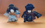 Par de bonecas orientais, com vestimentos tradicionais do Japão, rostos em porcelana - Dimensão cada: 14 X 12 cm