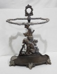 Porta guarda-chuvas confeccionado em antimônio com cinzelado representando cachorro, flores e folhagens, suporte no feitio de tronco, pés no feitio de folha. Possui falhas na esmaltagem. Medindo 69,5 x 24 x 50 cm