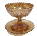 ANTIGA COMPOTEIRA EM VIDRO CARNIVAL GLASS DECORAÇÃO DITA GREGA COM PRESENTOIR. SEM A TAMPA. MEDINDO 15 X 16 CM E O PRESENTOIR 19 CM