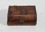 Caixa decorativa de madeira estilo baú, frequentemente usada como porta-joias ou lembrança, caracterizada por detalhes em metal e um aplique de camelo. Medindo 5 x 8 x 10.5 cm