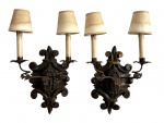 Par de palacianas arandelas francesas em madeira e movimentos em ferro fundido retorcido patinado, com dois braços de luz e detalhes em volutas e flor-de-lis. Apresentam douramento antigo e cúpulas em tecido original. Marcas do tempo. Parte elétrica necessita revisão. Peças de elegante desenho clássico, ideais para composição em interiores de estilo histórico. Meados século XIX. Mede 58cm x 35cm cada.