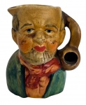 ENGLAND - Mini caneca figurativa em cerâmica inglesa, modelado como personagem masculino com barba e expressão pintada à mão, usando roupa colorida e segurando objeto em forma de cachimbo que funciona como alça. Peça popular decorativa, com desgaste natural do tempo, ideal para coleção de figuras utilitárias vintage. Mede 8,5 cm.