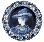 HOLANDA - Prato decorativo em faiança Delft Blue, Holanda, pintado à mão, com cena em azul cobalto representando Saskia, inspirada em obra de Rembrandt, conforme inscrição no verso (Saskia  naar Rembrandt). Peça assinada e identificada como handpainted  made in Holland, com suporte original para parede. Mede 25 cm diâmetro.