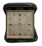 Relógio despertador de mesa Europa Suíça, mecanismo mecânico 7 jewels, mostrador metálico com marcadores aplicados e ponteiros dourados. Acompanha estojo original em couro, com sinais de uso e pátina do tempo, preservando o caráter vintage da peça. Funcionamento desconhecido. Mede 8 cm.