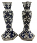 EUROPA - Par de castiçais em cerâmica, esmaltação branca com rica decoração floral em azul cobalto, detalhes em relevo e base facetada. Peças decorativas de bom acabamento, ideais para composição clássica.Mede 21 cm de altura.