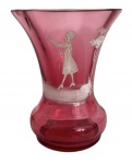 MARY GREGORY - Vaso em vidro artístico na tonalidade rubi, com decoração em camafeu representando figura feminina em branco opaco, aplicada manualmente. Corpo bojudo com boca em corneta, característico da produção inglesa do final do século XIX e início do século XX. Peça atribuída à escola de Mary Gregory, reconhecida por cenas figurativas delicadas sobre vidro colorido. Possui discreto bicado. Mede 8 cm.