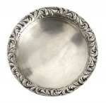 Salva/porta alianças em prata, formato circular, com borda trabalhada em relevo rococó e três pés. Superfície lisa central, verso com marca de contraste e sinais naturais do tempo. Peça decorativa ou de uso cerimonial, tradição europeia, final do século XIX / início do XX. Peso 30,8 g. Mede7 cm diâmetro.