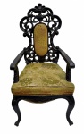 Poltrona de braços de estilo D. Maria I, em madeira escura ricamente entalhada, com espaldar vazado de desenho curvilíneo e braços integrados. Assento e encosto estofados em veludo, apresentando desgaste compatível com o tempo. Pés curvos, conferindo elegância e imponência ao conjunto.No estado. Mede 1,20 cm altura x 70 cm largura.