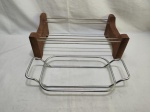 Lote de 2 suportes de pirex, sendo em madeira e metal prateado. Medindo o maior 42cm x 24cm de altura.