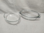 Lote de 2 travessas ovais fundas em vidro temperado, sendo uma com tampa. Medindo a maior 28cm x 17cm x 6,5cm de altura.