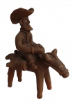 Escultura em terracota representando cavaleiro carregando madeira em cor natural e olhos pintados, assinado por Genivaldo. Artista brasileiro reconhecido internacionalmente. Medidas: Alt. 19 x C. 17 x L. 09 cm.