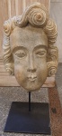 Escultura representando - Cabeça moldada em pedra sabão.                                                                                     Sustentação, por base de ferro.  Medidas com base: Altura 50 x 25 x 18 cm.  Só cabeça 38 x 25 x 18 cm.