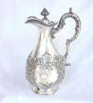 Jarra em estanho prateada, decoração em alto relevo, flores, com monograma em reserva  M  Marca: WALKER E HALL- SHEFFIELD ENGLAND.  (Apresenta amassado na base)  Medidas: Alt. 24 x 16 x 12 cm.