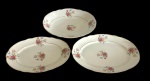 Real - Três travessas em porcelana. Decoração em policromia com motivos florais centrais e nas bordas, apresentando guirlandas e buquês de flores coloridas. Bordas levemente onduladas com acabamento em filete dourado. Medindo: 20,5 x 28 x 5,5 cm; 28 x 18 x 3 cm e 32 x 20,5 x 3,5 cm. Uma travessa apresenta um discreto bicado.