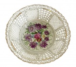 Hungria. Fruteira em porcelana vazada. Decoração central em policromia com motivos florais, corpo trabalhado em rendilhado vazado e bordas com acabamento em filete dourado. Medindo: 19 x 6 cm.
