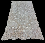 Toalha de mesa em renda trabalhada. Rica decoração em renda vazada com complexos motivos florais e arabescos, apresentando composição central em destaque e bordas recortadas com acabamento ondulado. Medindo: 300 x 160 cm.