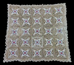 Toalha de mesa em renda com detalhes bordados. Composta por quadrados com desenho floral no centro em tons de rosa e azul, interligados por renda, com acabamento rendado nas bordas. Medindo: 125 x 130 cm.