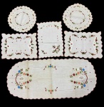 Conjunto com 6 peças em tecido bordado. Composto por toalhinhas e centro de mesa variados, com bordados florais coloridos e acabamento em bordas onduladas com medidas variadas.