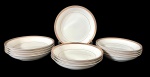 Doze pratos fundos em porcelana japosena na cor branca, decorada em tom dourado com padronagem geométrica contínua, além de filete fino próximo à área central. Manufatura no verso. Medindo: 26 cm.