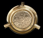 Cinzeiro em metal dourado com três apoios para cigarro, centro com relevo detalhado de pássaros e flores em estilo decorativo. Medindo: 12 cm.