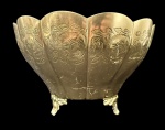 Fruteira em metal dourado com corpo facetado em formato de pétalas, borda ondulada e decoração em relevo com motivos florais e aves, apoiada sobre três pés. Medindo: 21 x 13 cm.