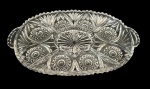 Petisqueira em cristal translucido no formato oval com alças laterais integradas e divisórias internas, incluindo compartimento central elevado para molhos. Rica lapidação geométrica em relevo com padrões radiais e florais, borda ondulada. Medindo: 34,5 x 21,5 x 3,5 cm.