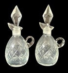 Par de frascos em vidro lapidado com tampa facetada e alça lateral e detalhes geométricos. Medindo: 17 x 7 x 9 cm. Tampas apresenta discreto bicado.